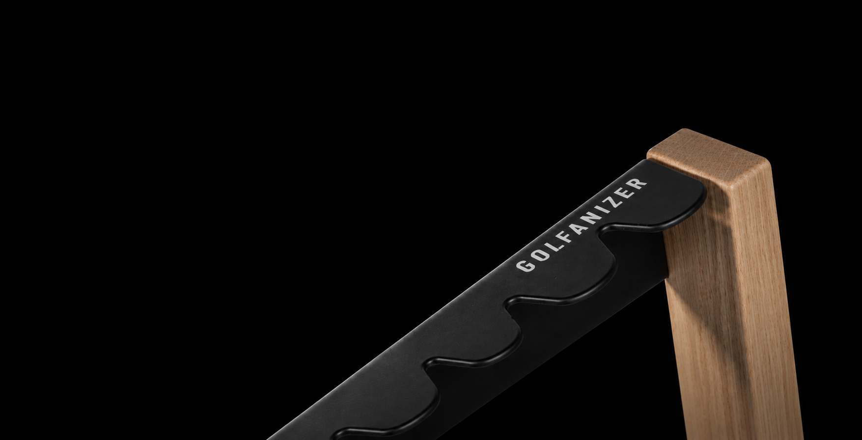 Close-up of the Golfanizer rack: soft-touch black steel club plate meeting a solid oak upright